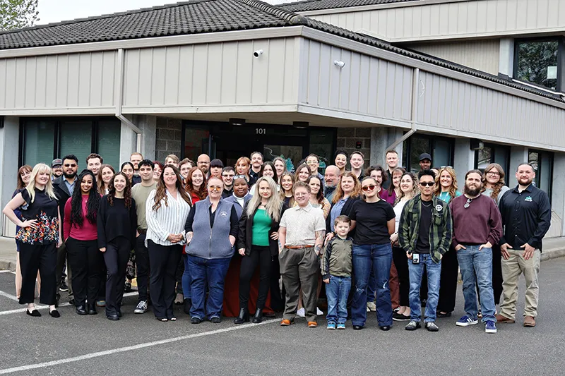 a large group of heritage employees stands gathered in front of the building