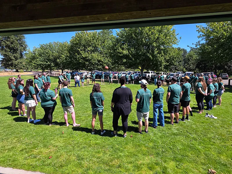 Heritage employees stand in a large circle on the grass.