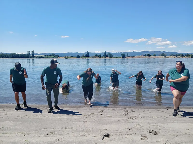 Heritage employees are all facing the camera and appear to be running. Some of them are in the water and some are on the beach.