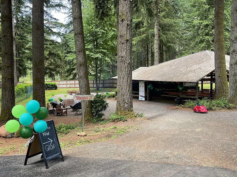 A covered pavilion surrounded by trees with Heritage NW Group decorations and signs