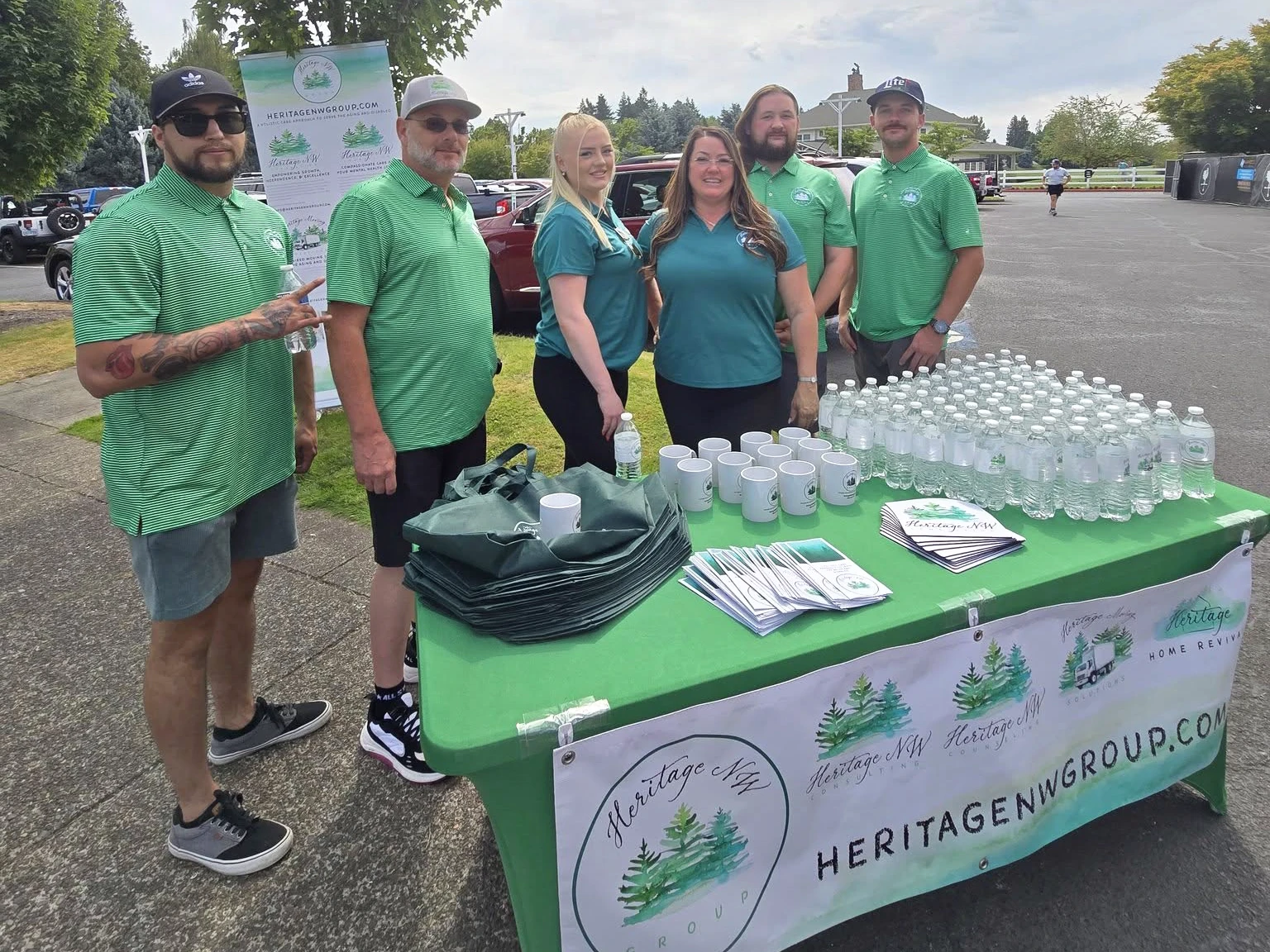 A group of Heritage employees at the service dog event stand behind the HNWG sponsorship table