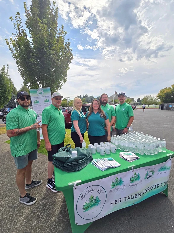 Heritage NW Group team stands together at their sponsorship table.