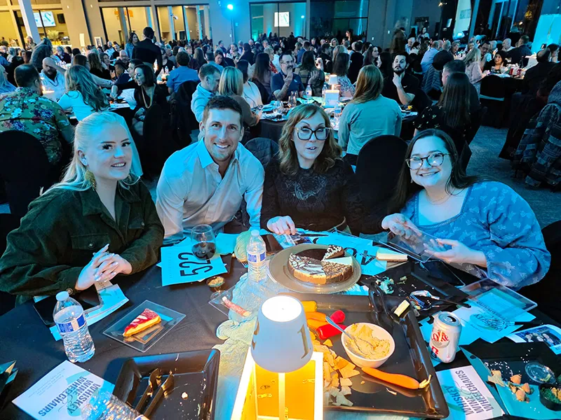 Heritage NW Group employees sit around a circular table with food and dessert dash cheesecake.