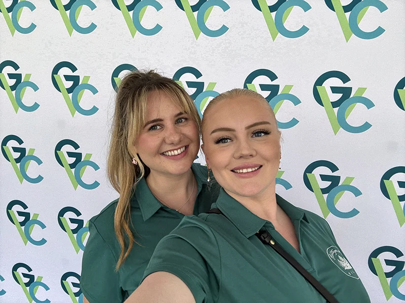 Miranda and Eryn pose and smile for a selfie in front of the GVC backdrop
