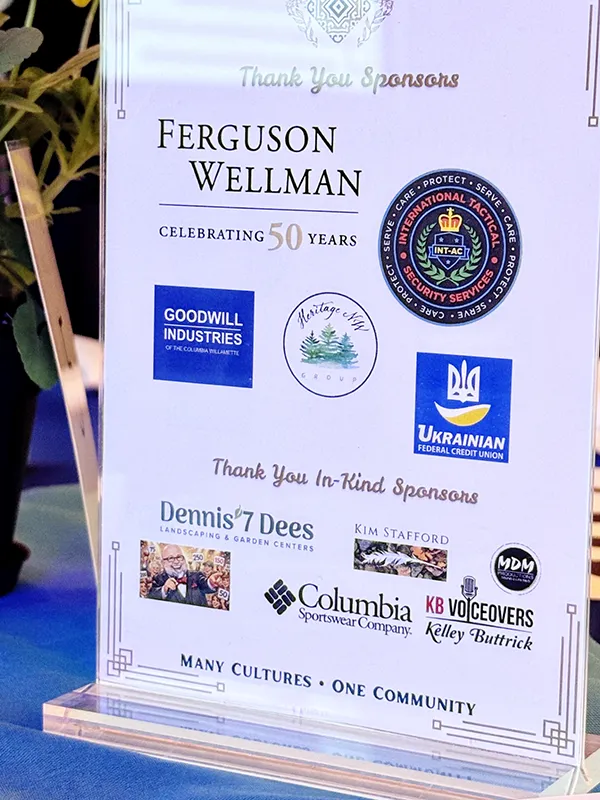 A sign thanking sponsors with their logos at Many Cultures, One Community. Ferguson Wellman, International Tactical Security Services, Goodwill Industries, Heritage NW Group, and Ukrainian Federal Credit Union are pictured as sponsors. Dennis 7 Dees, Kim Stafford, MDM, Columbia Sportswear Company, KB Voiceovers and an image of a bearded man holding a microphone are all listed under Thank you In-kind sponsors.