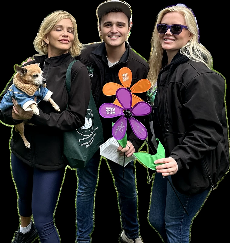 Three Heritage employees hold flowers and a small dog.